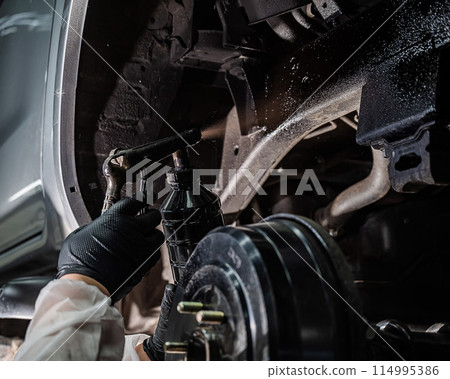 The master sprays an anti-corrosion compound on the bottom of the car. 114995386
