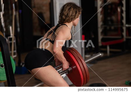 Middle-aged woman doing abdominal rows on a machine in the gym. Middle-aged woman doing abdominal rows on a machine in the gym. 114995675
