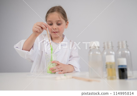 Caucasian girl doing chemical experiments on a white background. Making slime. Caucasian girl doing chemical experiments on a white background. Making slime. 114995814
