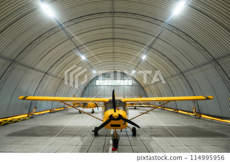 Yellow airplane glider in the hangar.  114995956