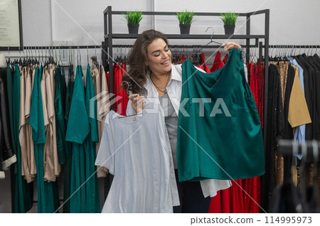 Smiling Caucasian fat woman choosing clothes. Plus size store.  114995973