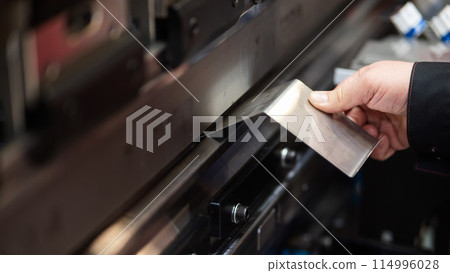 A master bends metal sheets on a machine. Hydraulic Press. A master bends metal sheets on a machine. Hydraulic Press. 114996028