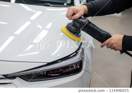 Process of polishing white car hood surface using orbital polishing machine.  114996055