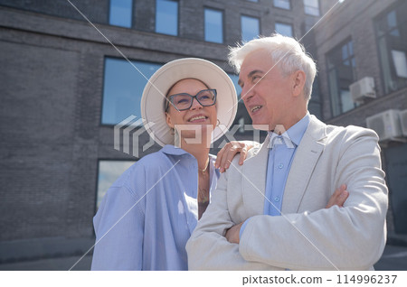 An elderly couple in love walks through the city. Portrait of a stylish gray-haired man and woman. An elderly couple in love walks through the city. Portrait of a stylish gray-haired man and woman. 114996237