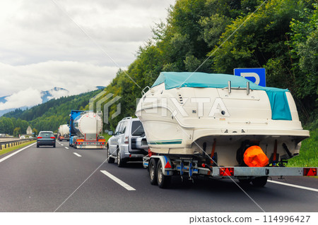 Modern luxury SUV towing yacht boat trailer carrier go river lake sea vacation mountain highway road summer light. Luxury rich fishing leisure recreation lifestyle. Service maintenance transportation Modern luxury SUV towing yacht boat trailer carrier go river lake sea vacation mountain highway road summer light. Luxury rich fishing leisure recreation lifestyle. Service maintenance transportation 114996427