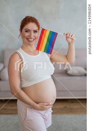 Happy pregnant woman holding a rainbow flag.  Happy pregnant woman holding a rainbow flag.  114996804