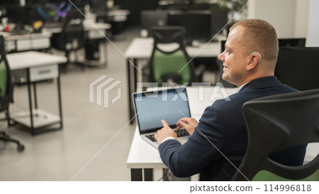 Caucasian deaf man typing on laptop in office.  114996818