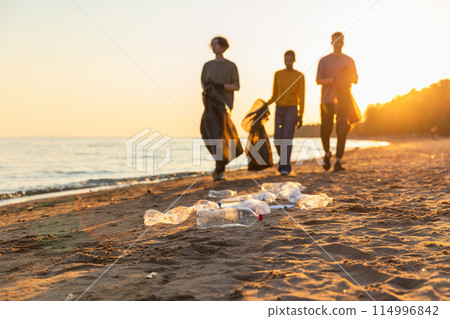 Earth day. Volunteers activists team collects garbage cleaning of beach coastal zone. Woman mans with trash in garbage bag on ocean shore. Environmental conservation coastal zone cleaning Earth day. Volunteers activists team collects garbage cleaning of beach coastal zone. Woman mans with trash in garbage bag on ocean shore. Environmental conservation coastal zone cleaning 114996842