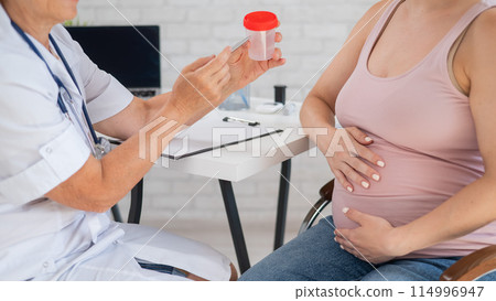 The doctor explains to a pregnant patient how to pass a urine test. The doctor explains to a pregnant patient how to pass a urine test. 114996947
