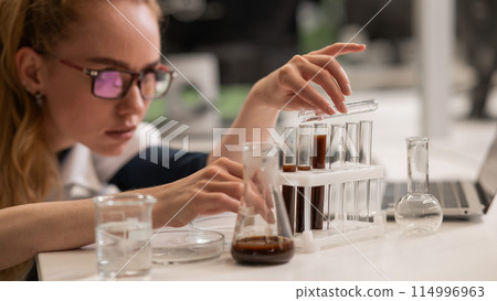 Caucasian woman in a medical gown doing laboratory experiments.  114996963