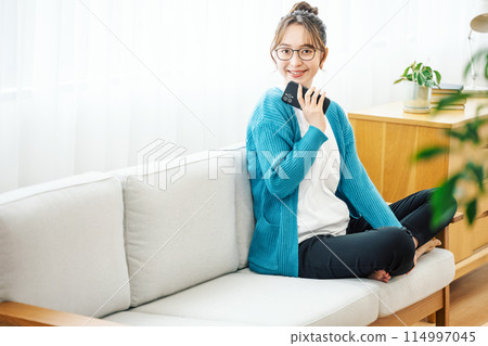 Woman with smartphone on sofa at home Woman with smartphone on sofa at home 114997045