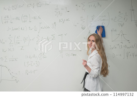 Caucasian woman erasing formulas from white board. Caucasian woman erasing formulas from white board. 114997132