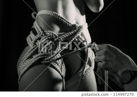 Man tightens ropes using Japanese shibari technique on woman's body 114997270