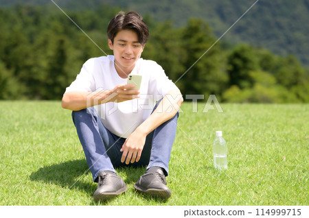 男人在草坪上看智能手機 114999715