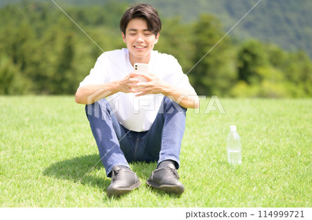 男人在草坪上看智能手機 114999721