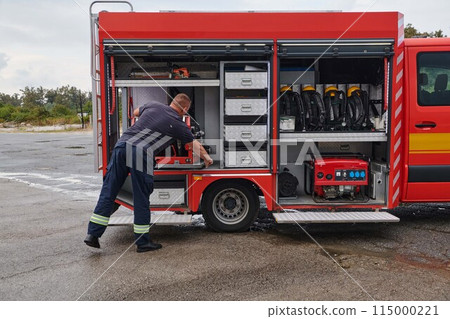 A dedicated firefighter preparing a modern firetruck for deployment to hazardous fire-stricken areas, demonstrating readiness and commitment to emergency response 115000221
