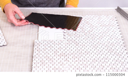 In the process of mounting peel and stick mosaic tiles onto a foam board, perfect for enhancing a food photography studio's aesthetic. 115000304