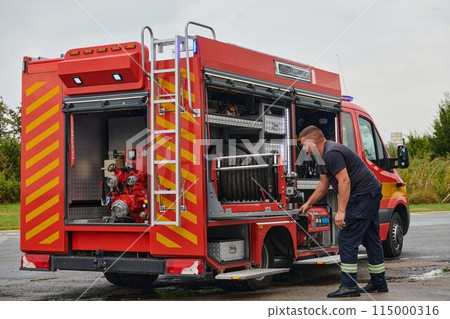 A dedicated firefighter preparing a modern firetruck for deployment to hazardous fire-stricken areas, demonstrating readiness and commitment to emergency response 115000316