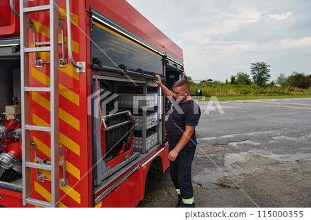 A dedicated firefighter preparing a modern firetruck for deployment to hazardous fire-stricken areas, demonstrating readiness and commitment to emergency response 115000355