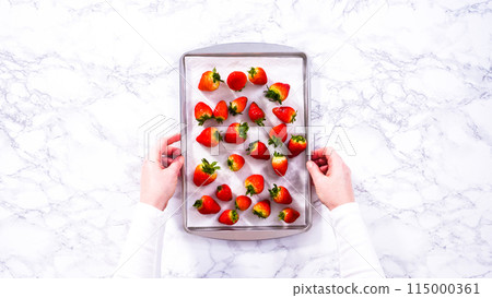 Flat lay. Juicy red strawberries, freshly washed, are spread out to dry on a baking sheet, carefully lined with paper towels to absorb excess moisture and prevent mold. Flat lay. Juicy red strawberries, freshly washed, are spread out to dry on a baking sheet, carefully lined with paper towels to absorb excess moisture and prevent mold. 115000361