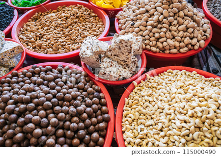 assortment of different varieties of nuts, dried fruits and Uzbek halva on counter at the oriental food bazaar in market stall assortment of different varieties of nuts, dried fruits and Uzbek halva on counter at the oriental food bazaar in market stall 115000490
