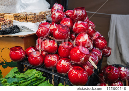 sweet candy apples on market shelf. Red caramel apples on sticks on the counter at the bazaar 115000548