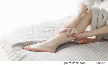 Woman massaging swollen legs Woman massaging swollen legs 115000584
