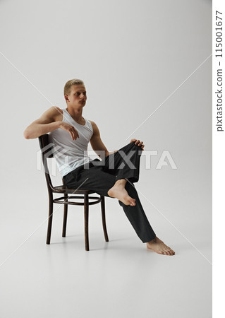 Young handsome confident man with muscular body posing on chair isolated on grey studio background. 115001677