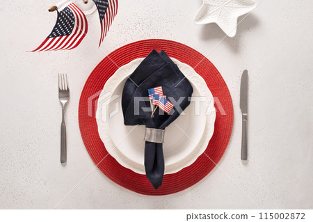 Patriotic table setting with American flag and decoration in national flag colors on white table. Independence Day. Happy Memorial Day. View from above. 115002872