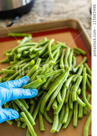 Watch as fresh green beans are beautifully roasted to perfection on a baking sheet with a silicone mat, adding a burst of flavor to your meal. 115003498