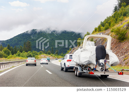 Modern luxury SUV towing yacht boat trailer carrier go river lake sea vacation mountain highway road summer light. Luxury rich fishing leisure recreation lifestyle. Service maintenance transportation Modern luxury SUV towing yacht boat trailer carrier go river lake sea vacation mountain highway road summer light. Luxury rich fishing leisure recreation lifestyle. Service maintenance transportation 115003529