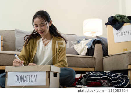 Woman preparing donation boxes at home. Concept of charity, giving, and community support Woman preparing donation boxes at home. Concept of charity, giving, and community support 115003534
