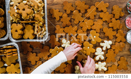 Flat lay. Crafting gingerbread cookie sandwiches with eggnog buttercream, presented on a rustic wooden table for Christmas gifting. Flat lay. Crafting gingerbread cookie sandwiches with eggnog buttercream, presented on a rustic wooden table for Christmas gifting. 115003558