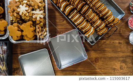 Flat lay. Lovingly homemade gingerbread and sugar cookies, half-dipped in rich chocolate, nestled in decorative Christmas tin boxes perfect for seasonal gifting. 115003617