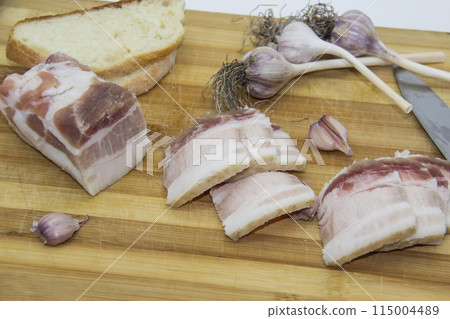 Ukrainian products raw lard with peppercorn and garlic, knife, slices of bread, salo lying on wooden board. Ukrainian traditional food concept. Ukrainian products raw lard with peppercorn and garlic, knife, slices of bread, salo lying on wooden board. Ukrainian traditional food concept. 115004489