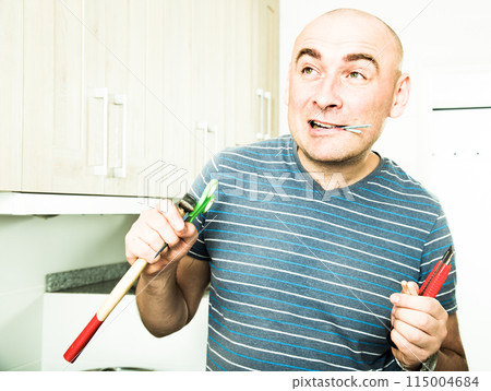 Imposing man iholds in teeth of screws and holding hammer 115004684