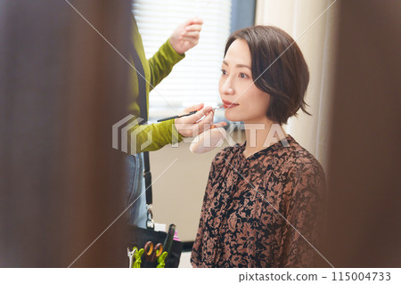 A model being applied by a makeup artist 115004733