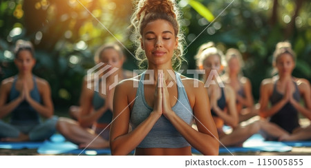 Group of adults attending a yoga class outside in park with natural background 115005855
