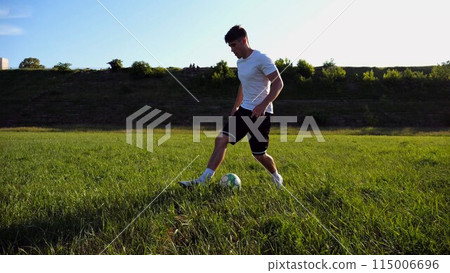 Professional footballer in uniform shows tricks with ball while running at green field. Sportsman kicks ball during jogging at meadow on sunny day. Young man training at stadium. Freestyle football Professional footballer in uniform shows tricks with ball while running at green field. Sportsman kicks ball during jogging at meadow on sunny day. Young man training at stadium. Freestyle football 115006696