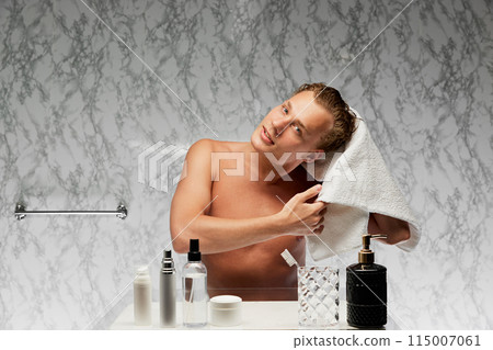 Young shirtless man using towel after shower against marbled wall in bathroom. Young guy getting prepared for working day 115007061