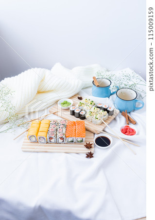 Sushi delivery. Set of rolls in a disposable box on a black background. Top view 115009159