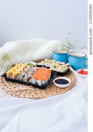 Sushi delivery. Set of rolls in a disposable box on a black background. Top view 115009160
