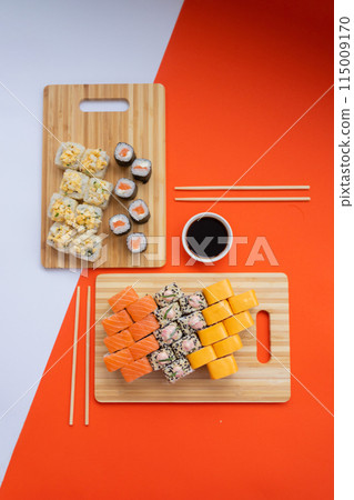 Sushi delivery. Set of rolls in a disposable box on a black background. Top view 115009170
