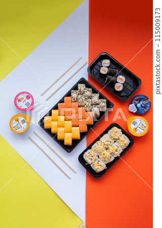 Sushi delivery. Set of rolls in a disposable box on a black background. Top view 115009173