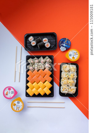 Sushi delivery. Set of rolls in a disposable box on a black background. Top view 115009181