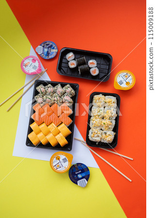 Sushi delivery. Set of rolls in a disposable box on a black background. Top view 115009188