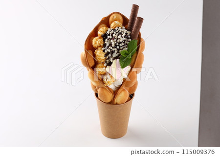 Trendy Hong Kong bubble waffles with ice cream, cream and berries on white wooden background. Copy space 115009376