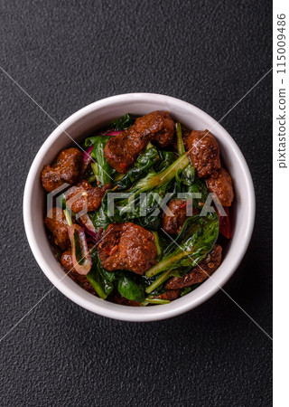 Delicious warm salad with pieces of meat, spinach, tomatoes, salt, spices and herbs 115009486