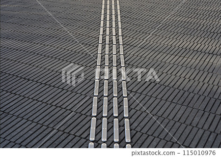 A close-up background photo of guiding blocks for visually impaired people installed on a sidewalk 115010976