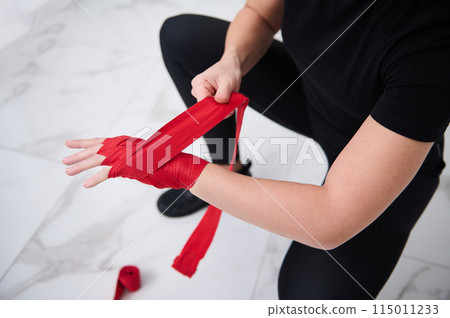 Top view of an Caucasian boxer fighter woman in black sports wear, tying tape around her hand before get boxing gloves preparing to boxing practice. 115011233
